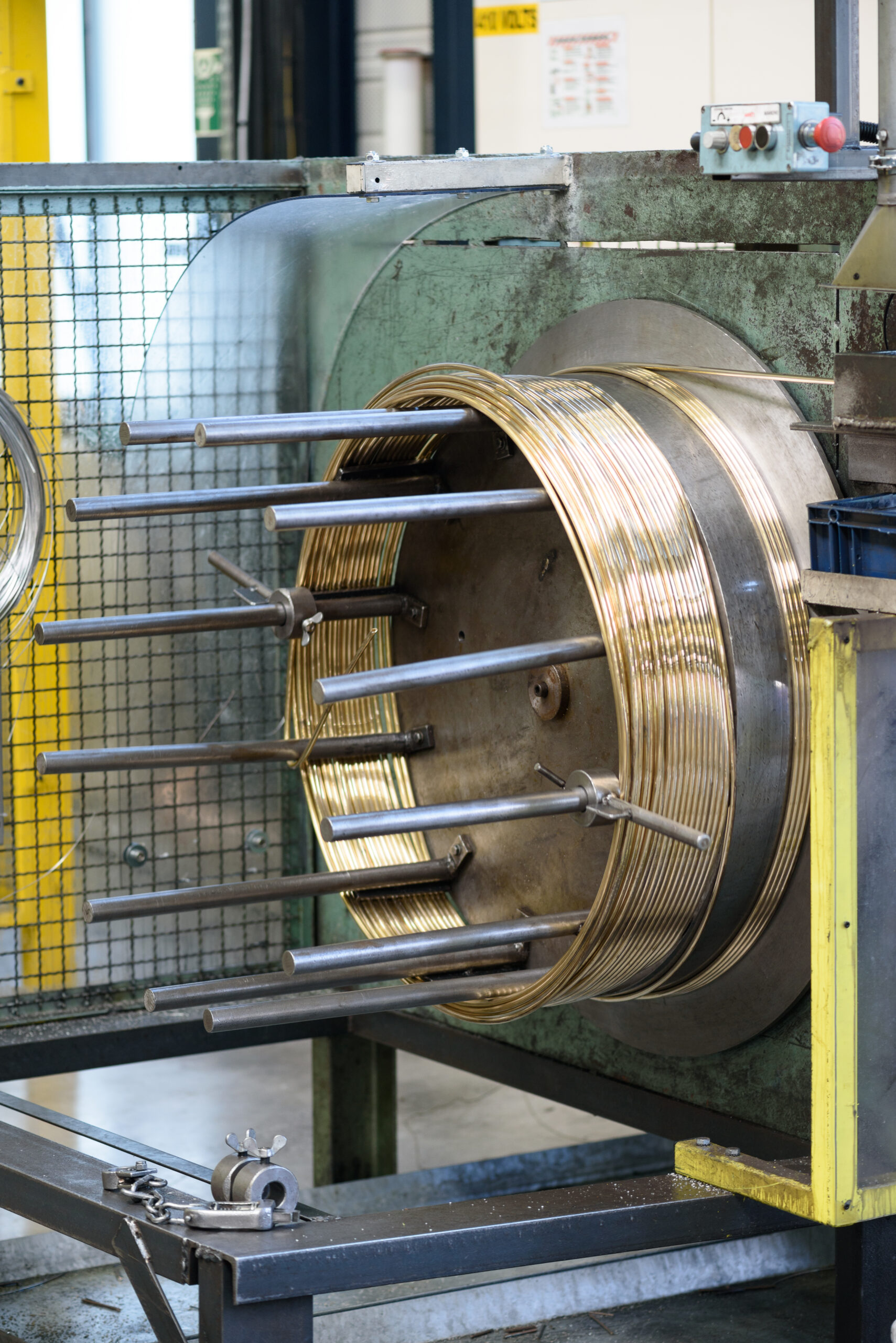 Machine industrielle en cours d'enroulement d'un fil métallique doré.