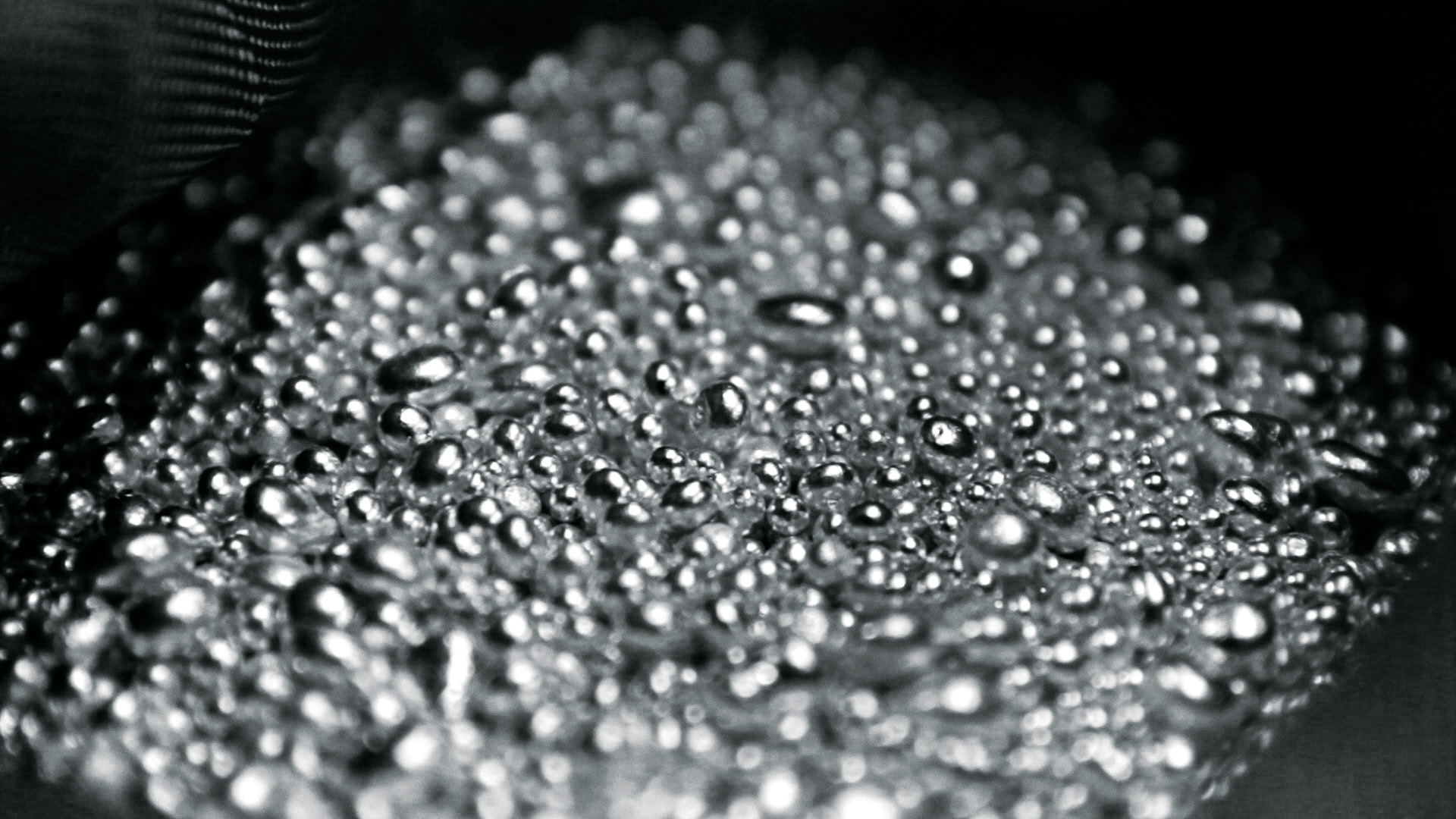 Gouttes d'eau ou de liquide sur une surface sombre, visibles en gros plan