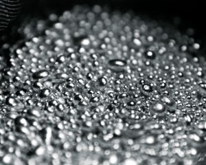 Gouttes d'eau ou de liquide sur une surface sombre, visibles en gros plan